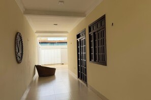 Un pasillo con suelo de baldosas, una puerta con reja metálica y un adorno fijado a la pared.