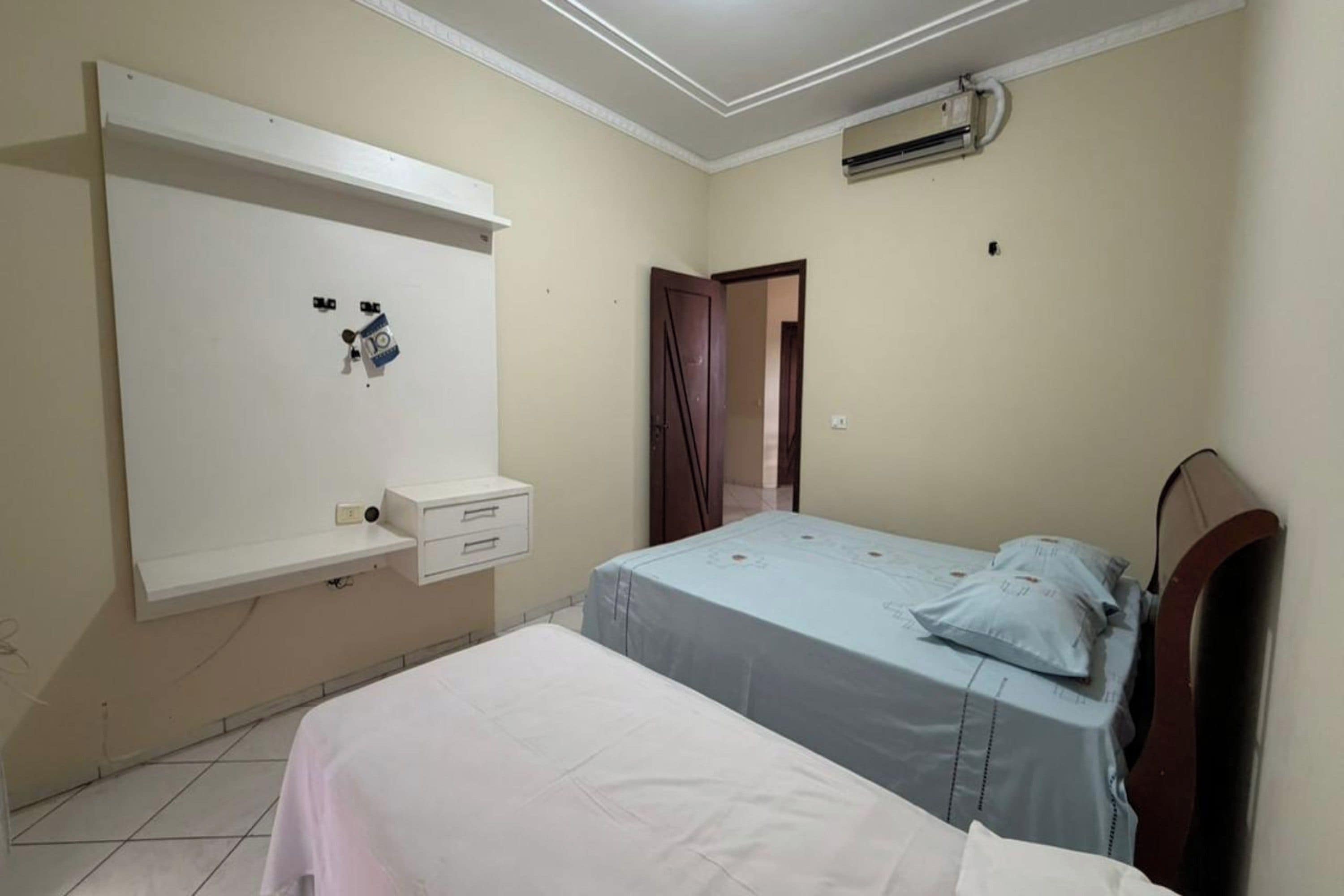 Un dormitorio con cama, mesita de noche, armario y aire acondicionado.