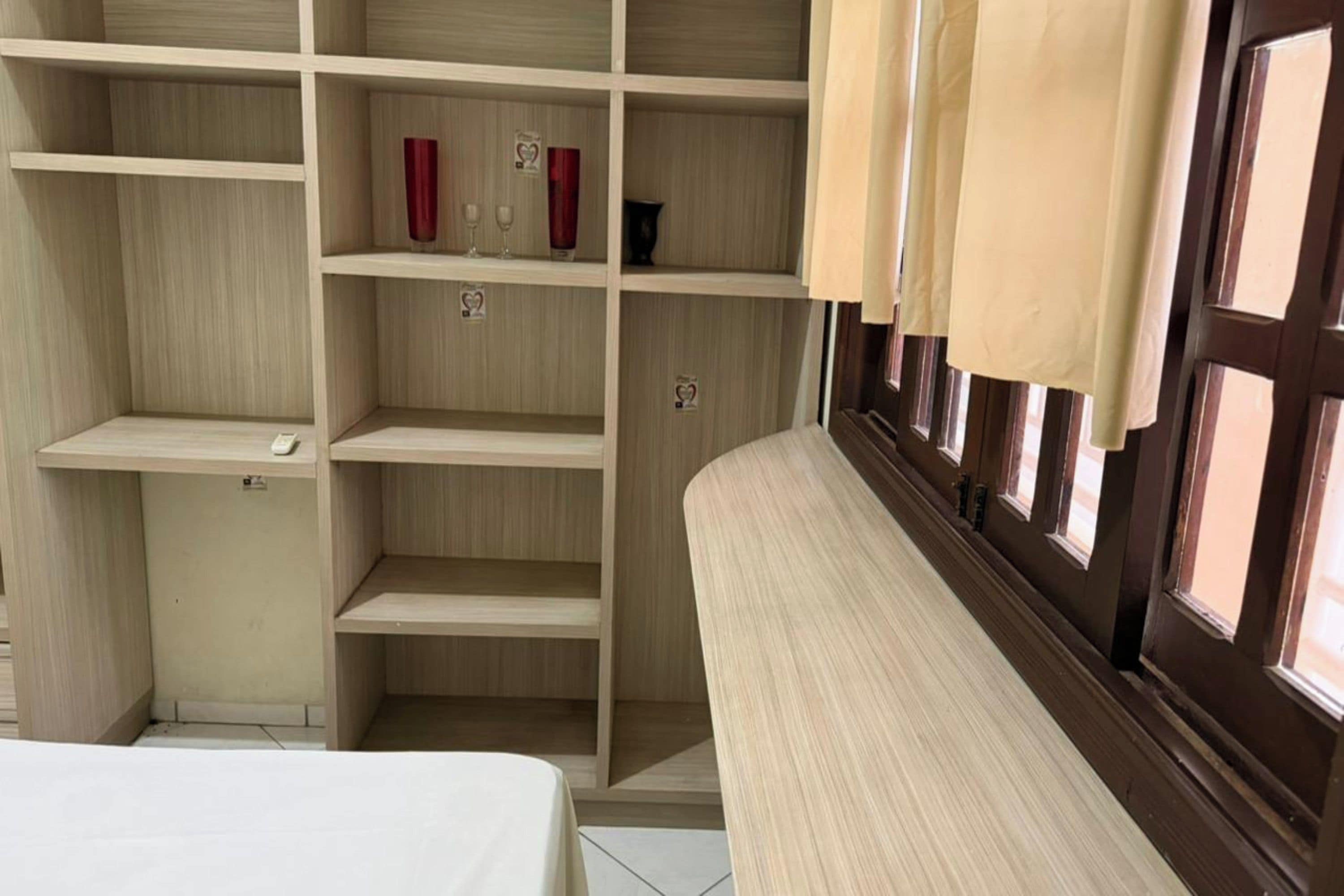 Una habitación con un amplio armario de madera, una cama y una ventana con cortinas.