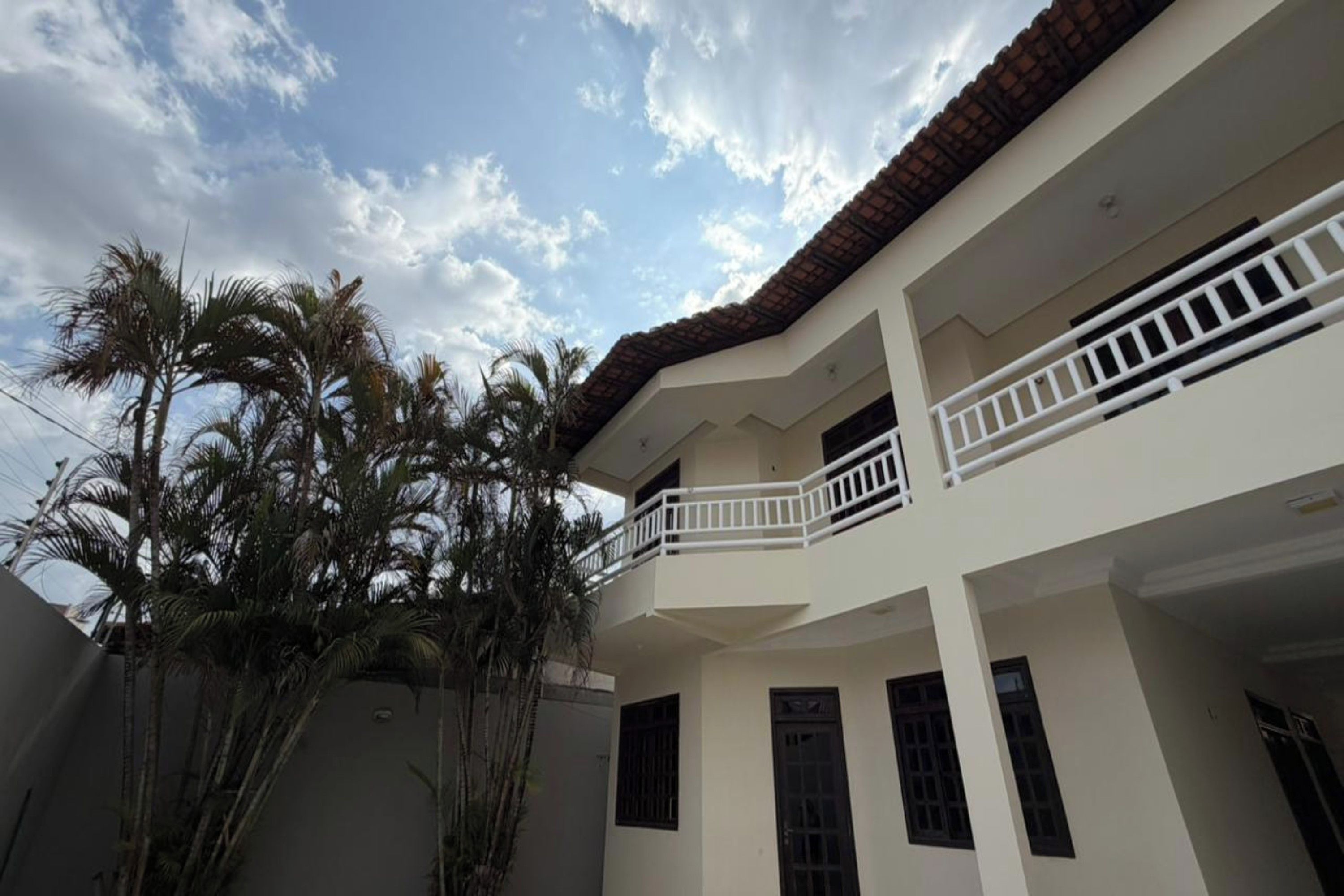 Un edificio de varios pisos con balcones, techo de tejas y cielo despejado.