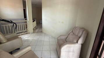 Een woonkamer met een beige bank, een stoel en een trap die naar een ander niveau leidt.