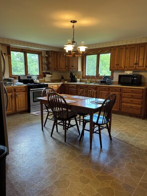 A kitchen with wooden cabinets, a dining table with chairs, a stove, and a microwave. - Cozy 1-bedroom house in pleasant Guilford with AC (Guilford)