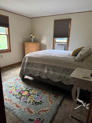 A bedroom with a bed, a dresser, a nightstand, and a window with blinds. - Cozy 1-bedroom house in pleasant Guilford with AC (Guilford)