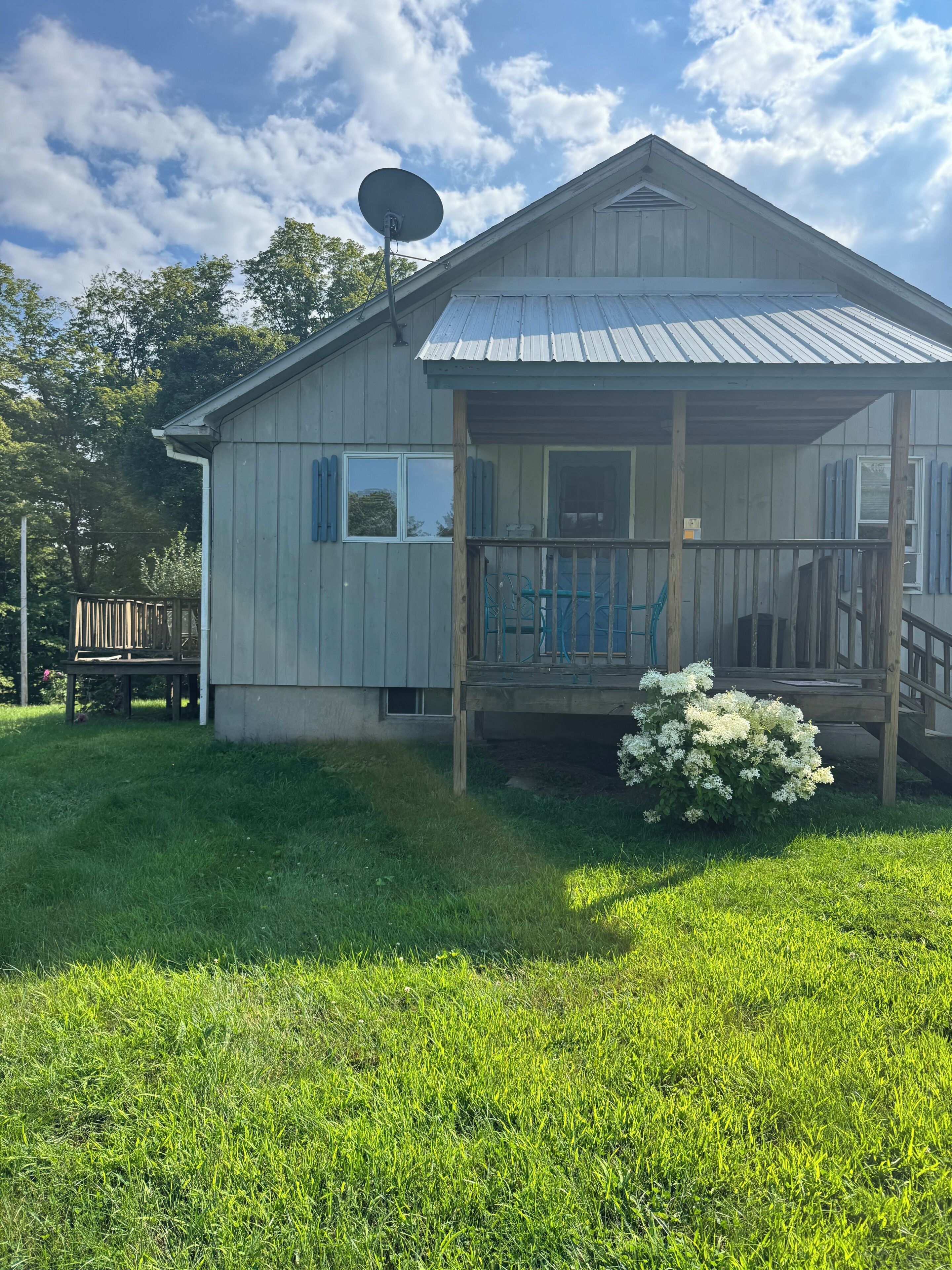 A single-story house with a porch, a satellite dish, and a small garden.