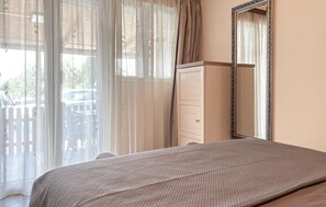 A bedroom with a bed, a dresser, a mirror, and a view of the outside. - Nice home in Porec with swimming pool (Porec)