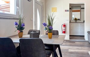 A dining area with a wooden table, two potted plants, and a fire extinguisher on the wall. - Nice home in Porec with swimming pool (Porec)