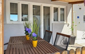 A wooden table with chairs, a window with curtains, and a wall with a fence. - Nice home in Porec with swimming pool (Porec)