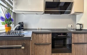 A modern kitchen with wooden cabinets, a built-in oven, a coffee machine, and a kettle. - Nice home in Porec with swimming pool (Porec)