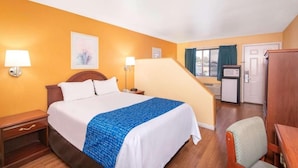 Une chambre d’hôtel équipée d’un lit, de tables de chevet, d’un bureau, d’une chaise, d’un four à micro-ondes et d’une porte.