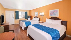 A hotel room with two beds, a desk, a television, and a window with curtains.