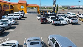 Un parking avec plusieurs voitures et un bâtiment doté d’un toit rouge.