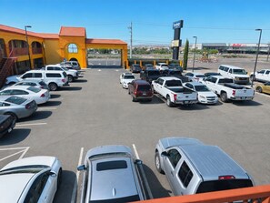A parking lot with multiple cars and a building with a red roof.