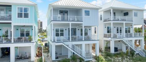 A beachfront residential area with multi-story houses featuring balconies and staircases leading to upper floors.