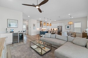 A modern living room with a glass coffee table, a sofa, and a ceiling fan. - Yacht Harbor House (Pensacola)
