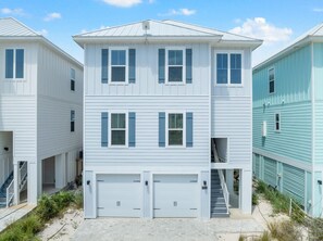 A two-story residential building with a garage, a covered walkway, and a staircase leading to the upper floor. - Yacht Harbor House (Pensacola)