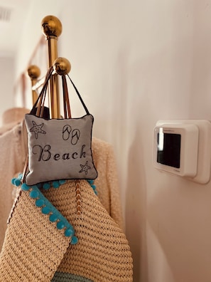 A room with a wall-mounted thermostat and a decorative item resembling a beach bag with the word 'Beach' on it. - Orchid Studio close to Selby Botanical Gardens, central air conditioning/heat (Sarasota)