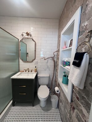 A bathroom with a white toilet, a sink with a mirror, and a towel rack. - Orchid Studio close to Selby Botanical Gardens, central air conditioning/heat (Sarasota)