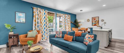 A modern living room with a sofa, a coffee table, and a dining area with chairs.