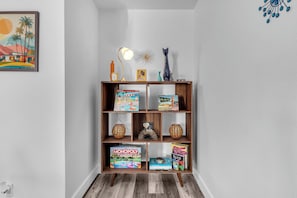 A wooden bookshelf with books, decorative items, and a lamp. - Indian Wells Condo, Steps to Pool,  Minutes to La Quinta El Paseo and Coachella (Indian Wells)