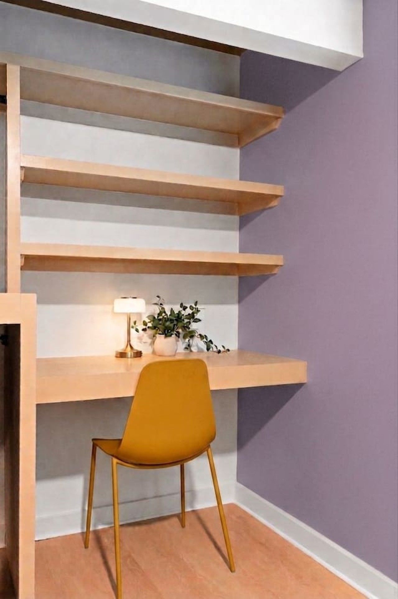 Un espace de travail aménagé dans un coin, comprenant un bureau, une chaise, des étagères et une lampe.