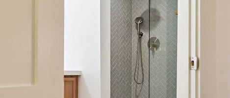 Ein modernes Badezimmer mit einer gläsernen Dusche, einem Holzkasten und einer weißen Tür.