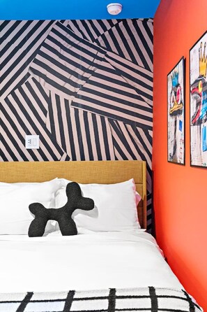 A room with a bed, a striped wall, and two framed artworks. - Designer 1BR | Sleeps 4 | Free Parking (Houston)
