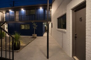 En modern byggnad med en blå fasad, en gång av betong och en dörr som är numrerad med 15.