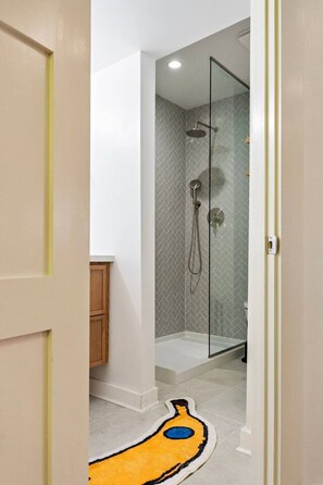 Ein modernes Badezimmer mit Duschkabine aus Glas, einer sichtbaren Toilette und einem Holzschrank.