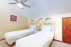 A bedroom with two single beds, a ceiling fan, a framed picture, and decorative items on the wall. - Sweet Alabama (Gulf Shores)