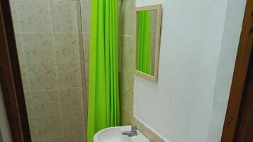 A bathroom with a toilet, sink, and green shower curtain.
