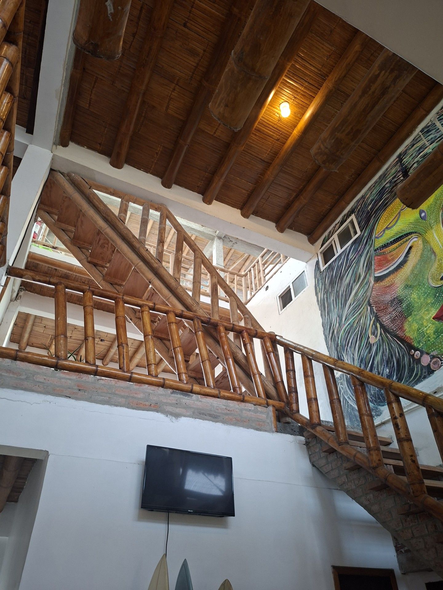 A wooden staircase with a handrail leading to an upper level. A flat-screen TV is mounted on the wall below.