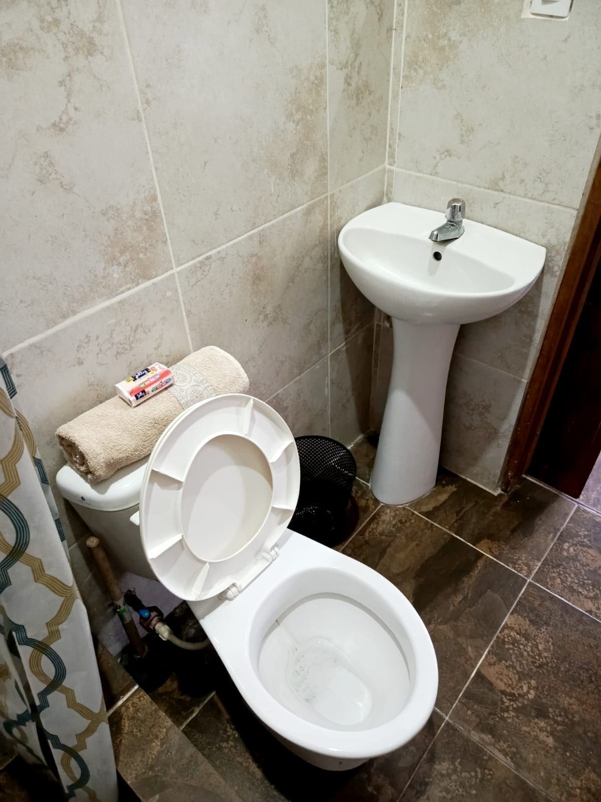 Un baño con inodoro, lavamanos y cortina de ducha.