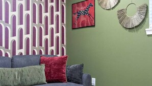 A living room with a grey sofa, a white coffee table, a patterned rug, and wall art. - Designer 1BR | Sleeps 4 | Near DT (Houston)