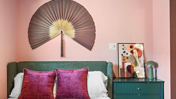 A bed with two pillows, a nightstand with a lamp, and a wall-mounted fan. - Designer 1BR | Sleeps 4 | Near DT (Houston)