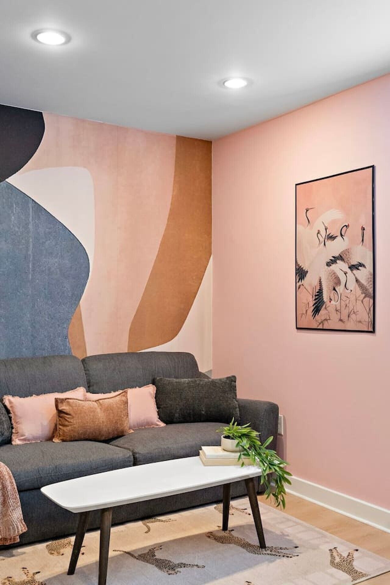 Una sala de estar moderna con un sofá gris, una mesa de centro blanca y un cuadro abstracto grande en la pared.