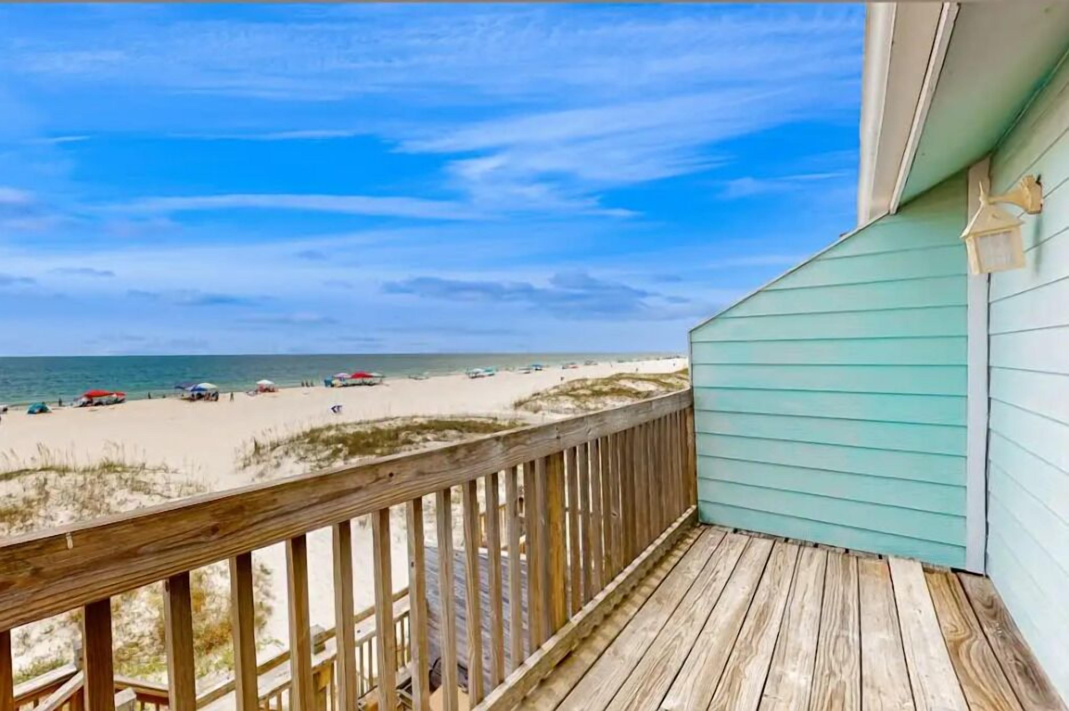 A wooden deck with a view of a beach and ocean.
