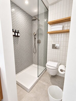 A modern bathroom with a glass-enclosed shower, a toilet, and a white tiled wall. - Downtown 1BR | DT Houston | Sleeps 4 (Houston)