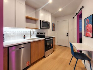 A modern kitchen with built-in appliances, a dishwasher, and a dining area with a table and chairs. - Downtown 1BR | DT Houston | Sleeps 4 (Houston)