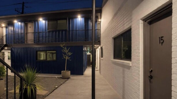 Un bâtiment à deux étages, avec une façade bleue et une porte blanche portant le numéro 15.