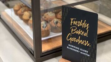 A bakery display case with muffins and a sign that reads 'Freshly Baked Goodness.'