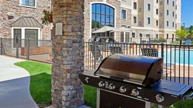 A stone pillar, a barbecue grill, and a poolside area with umbrellas. - Accessible 1BR Suite | Free Daily Breakfast + Pool (Denton)