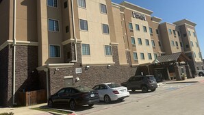 A multi-story hotel with a beige facade, multiple windows, and a sign for Staybridge Suites. - Accessible 1BR Suite | Free Daily Breakfast + Pool (Denton)