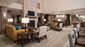 A hotel lobby with a stone fireplace, seating areas, and a bar. - Accessible 1BR Suite | Free Daily Breakfast + Pool (Denton)