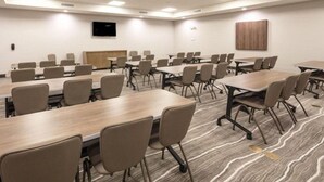 A conference room with multiple tables and chairs, a flat-screen TV mounted on the wall, and a wooden panel on the back wall. - Accessible 1BR w/ 2 Queens | Hot Breakfast + Pool (Denton)