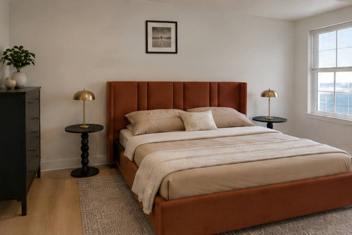 A bedroom with a bed, bedside tables, a dresser, a window, and a framed picture on the wall.