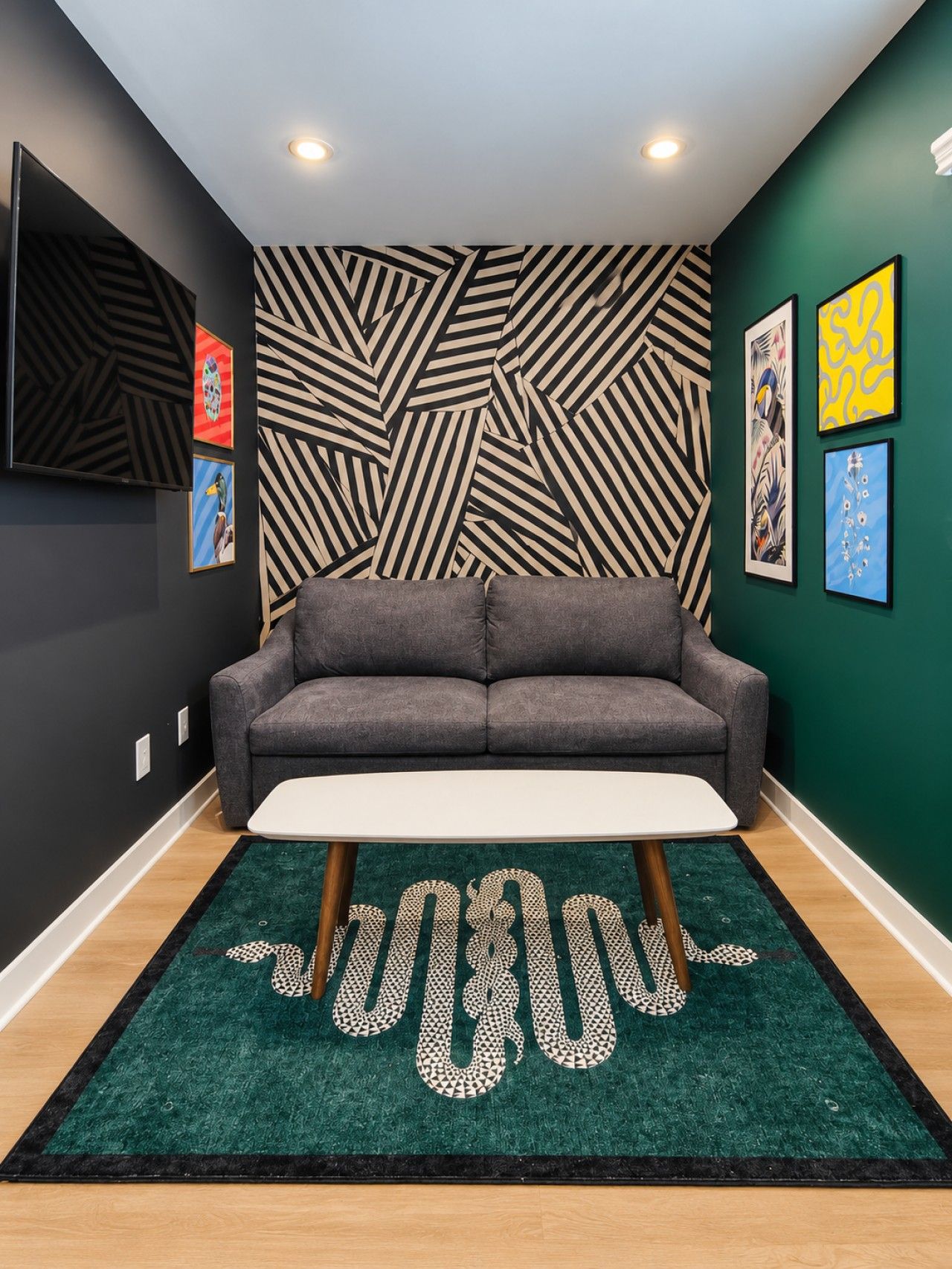 Un salon moderne avec un canapé gris, une table basse blanche et un tapis à motifs.