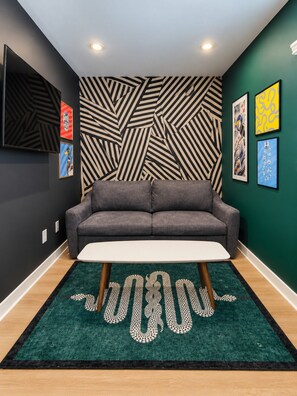 A modern living room with a grey sofa, a white coffee table, and a patterned rug. - 1BR Designer Suite | Sleeps 4 (Houston)