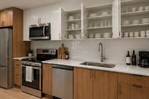 Eine moderne Küche mit Edelstahlgeräten, Holzschränken und einem eingebauten Weinkühlschrank.