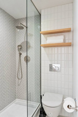 A modern bathroom with a glass shower enclosure, a toilet, and a towel rack. - Trendy 1BR | DT Houston | Sleeps 4 (Houston)
