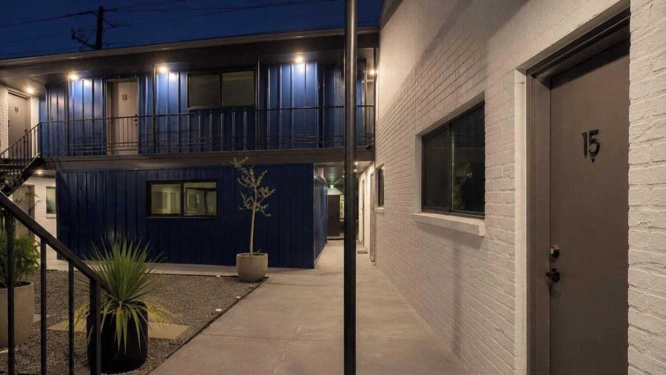 A modern building with a blue exterior, a concrete staircase, and a door marked with the number 15.